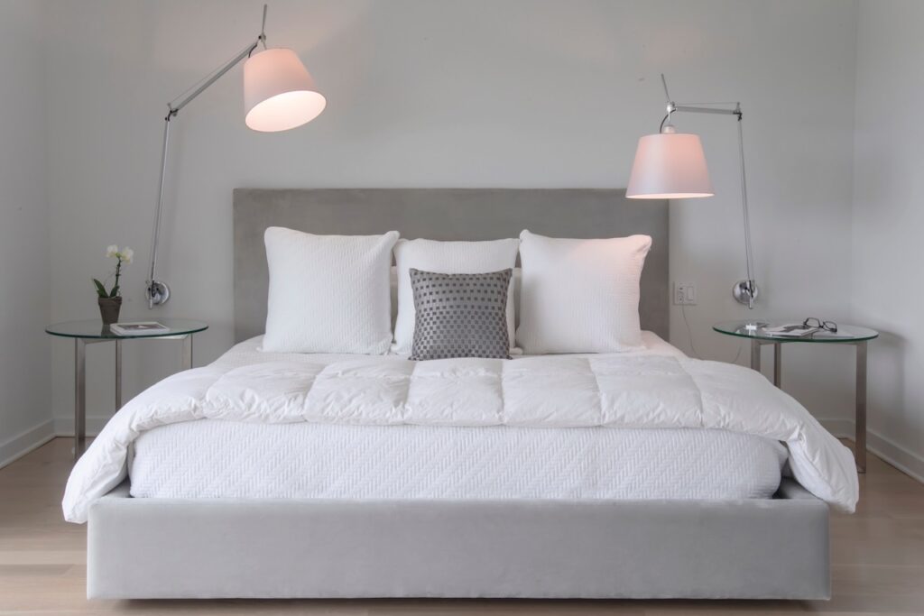 Artemide Tolomeo Mega wall lamp with a fabric shade on an adjustable arm, lighting a bed in a calm grey bedroom