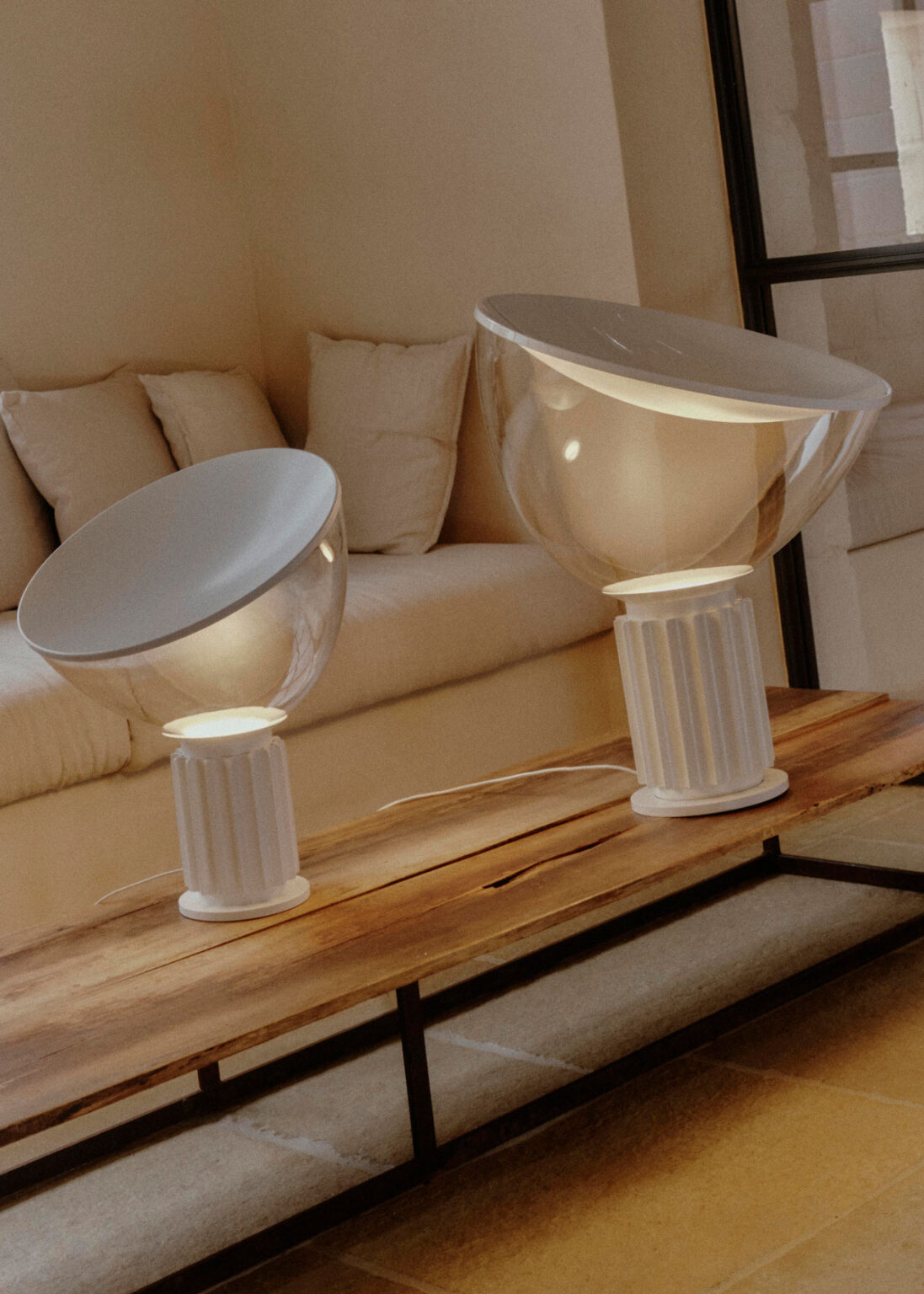 Flos Taccia table lamp in matte white beside a sofa