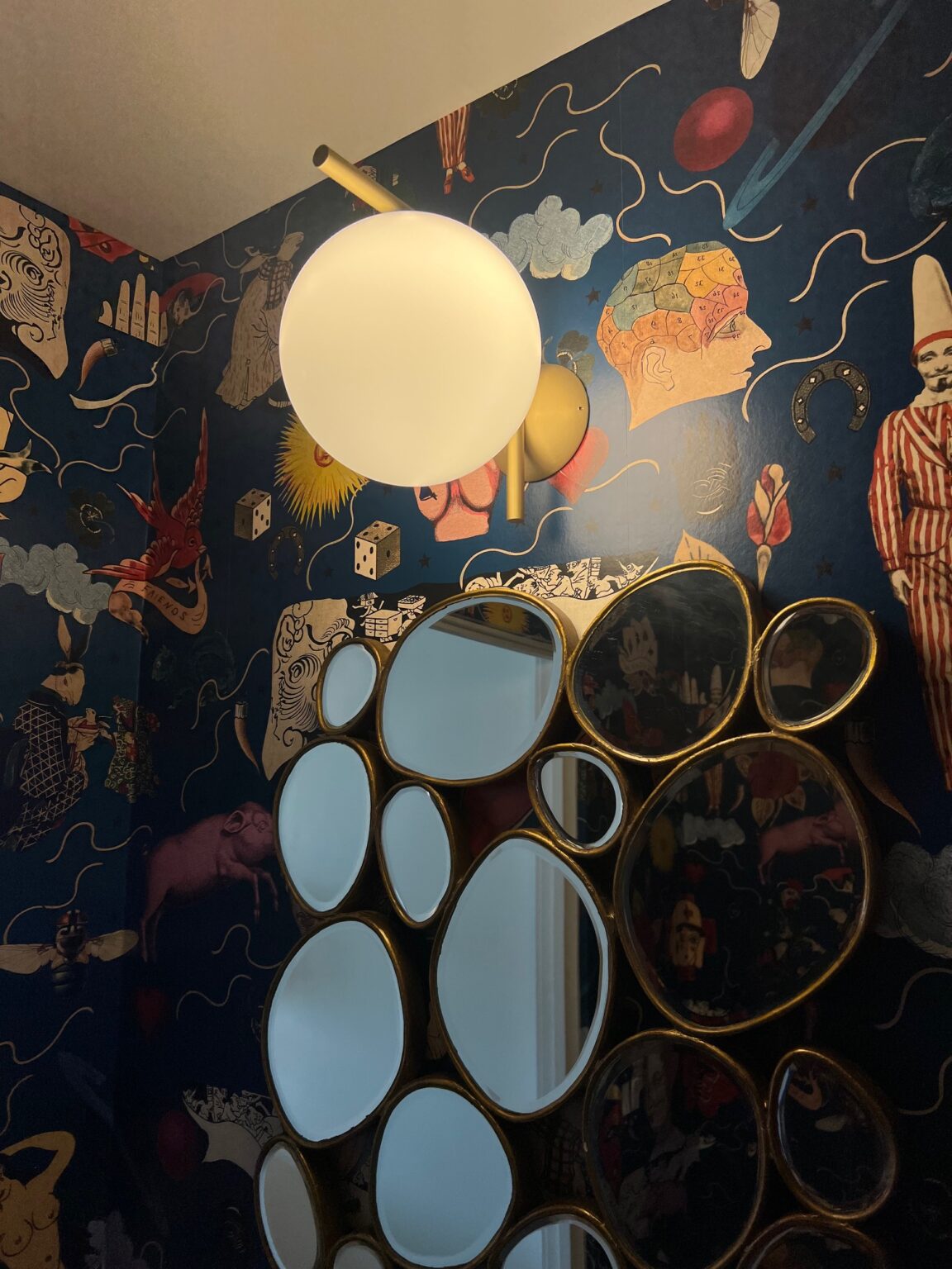 Flos IC Lights wall fixtures against a dark patterned wallpaper