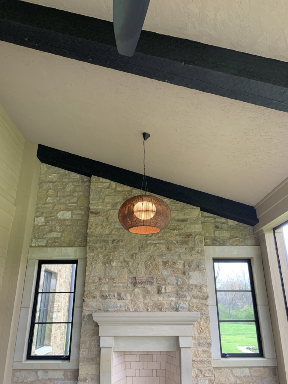 Bover Garota pendant in front of a stone fireplace