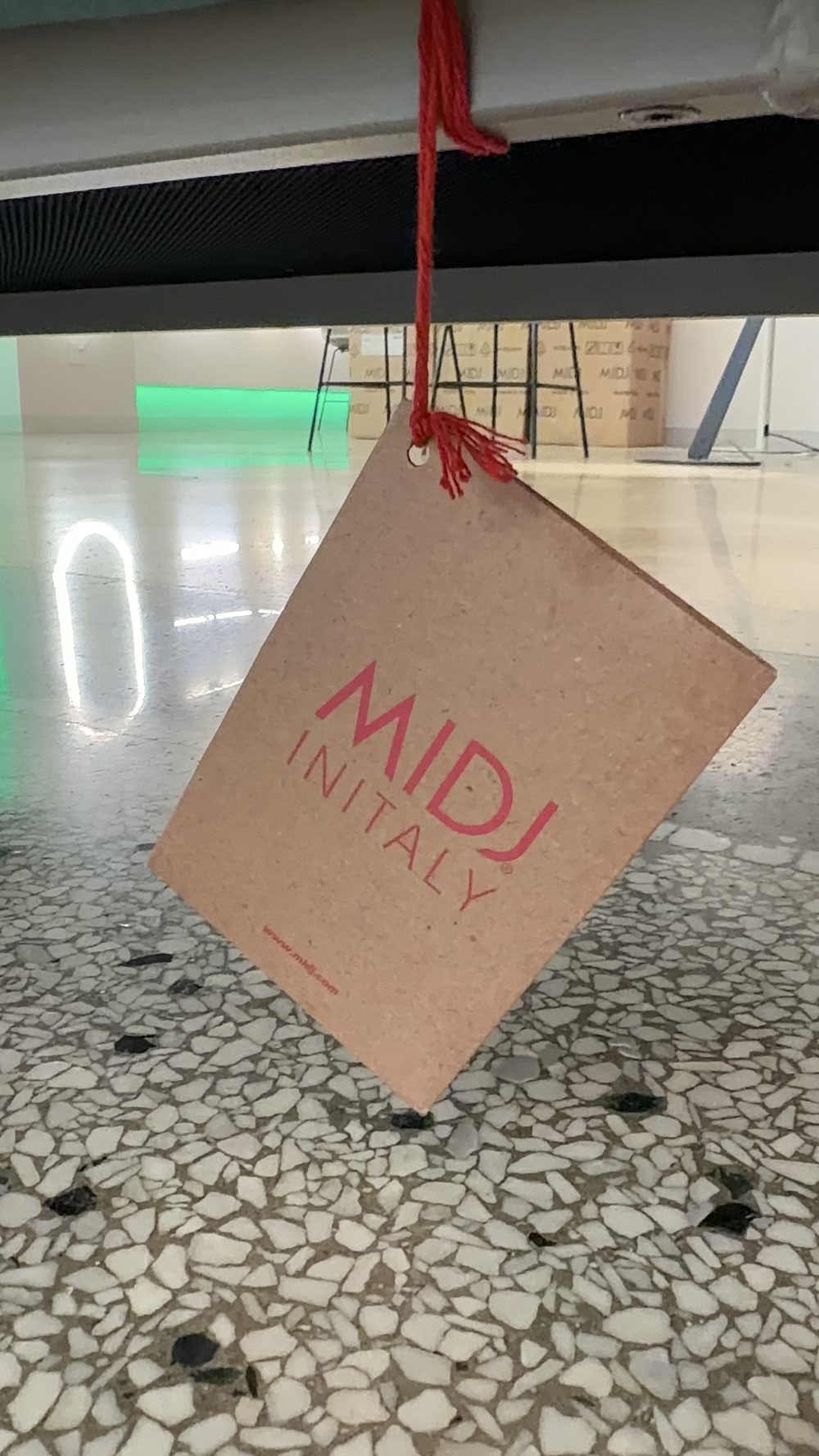 Kraft Midj In Italy hang tag on red string beneath the Area Chaise, with Midj shipping boxes behind
