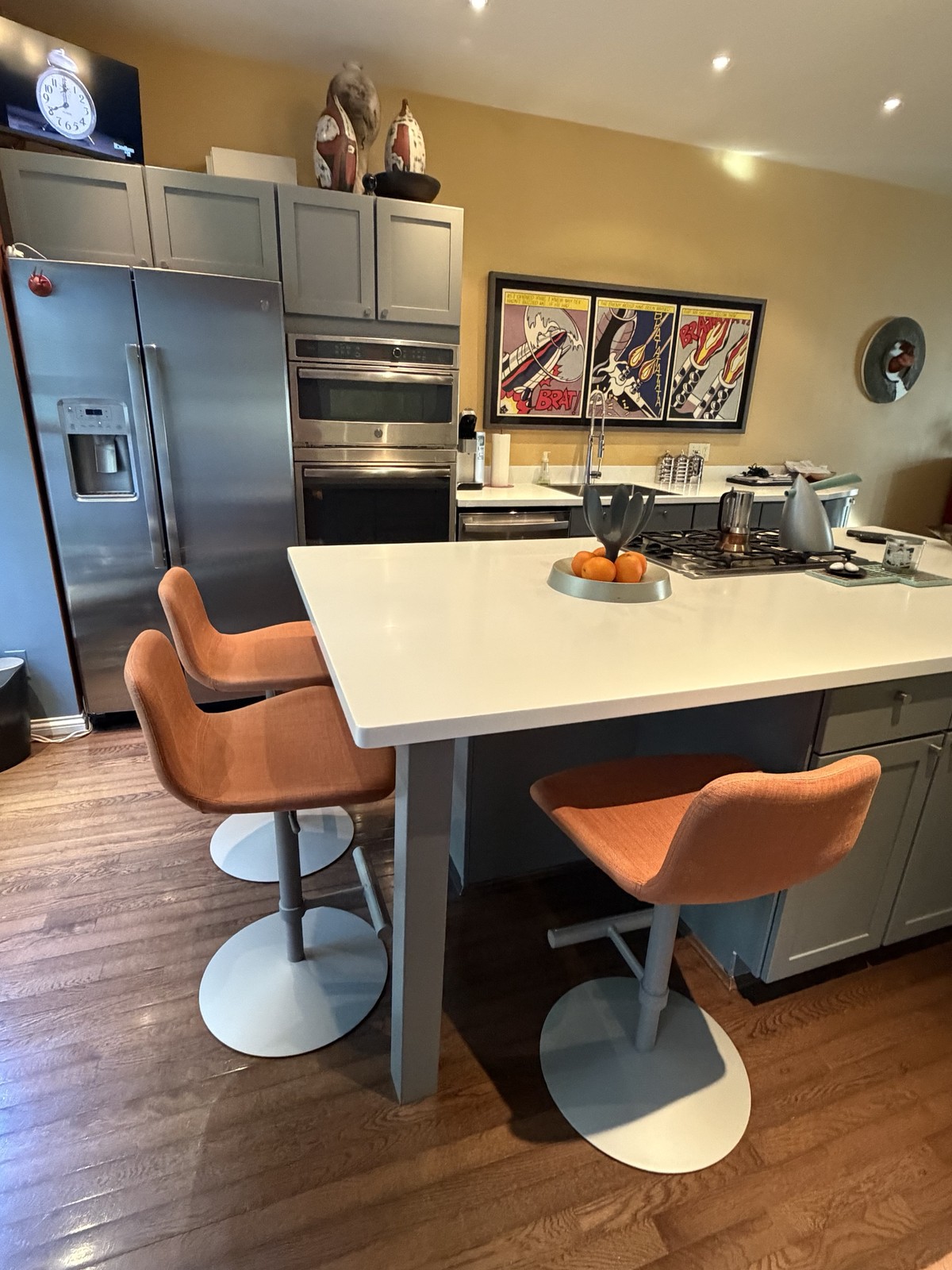 Three Midj Dalia counter stools in orange fabric at a white quartz kitchen island in Cincinnati