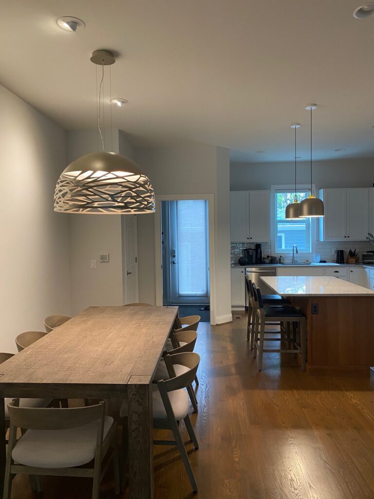 A Kelly dome over a long dining table with JIM bells over the kitchen beyond