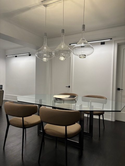 Three clear Sky-Fall pendants in a row over a glass dining table
