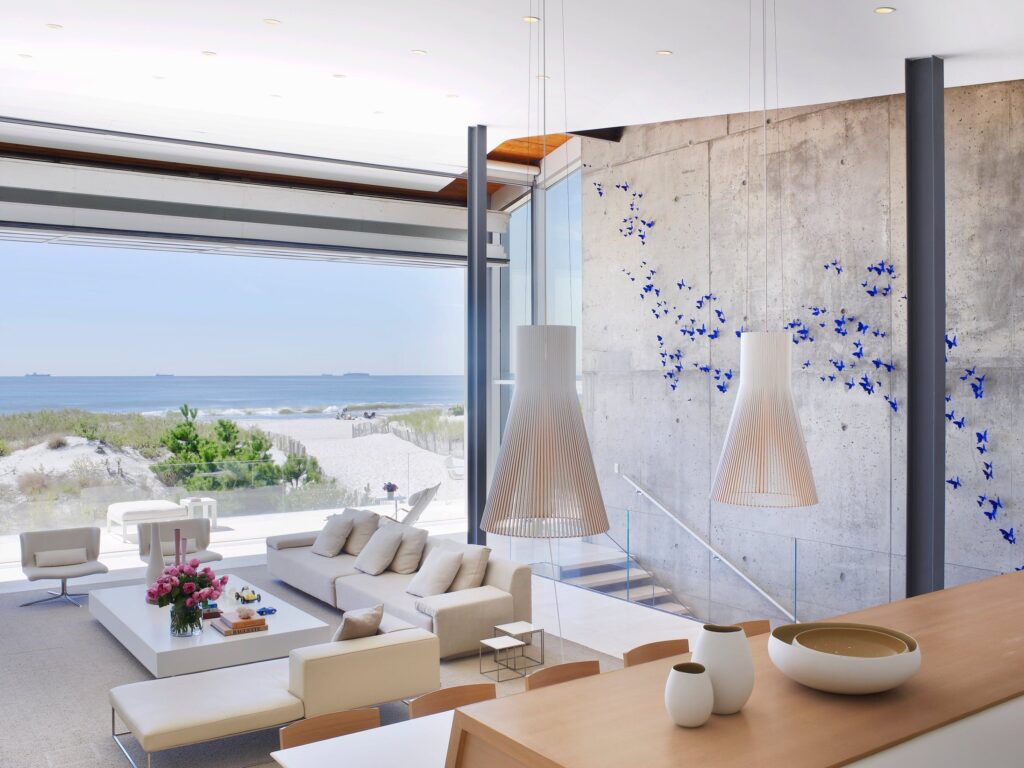 Two tall Magnum 4202 wooden pendants in an open living room with an ocean view, Long Island, New York