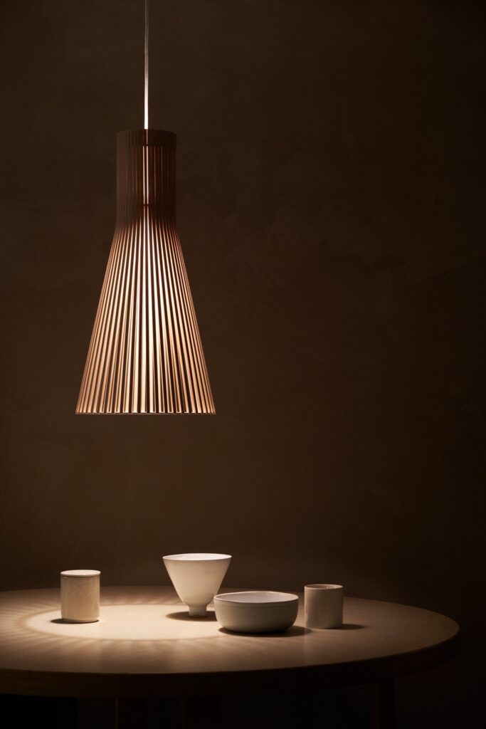Secto 4200 wooden pendant casting a warm pool of light over white ceramics on a round table
