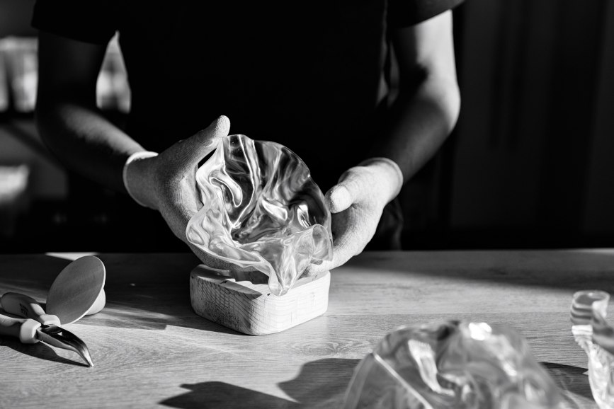 Hands shaping a Slamp lamp component in the workshop