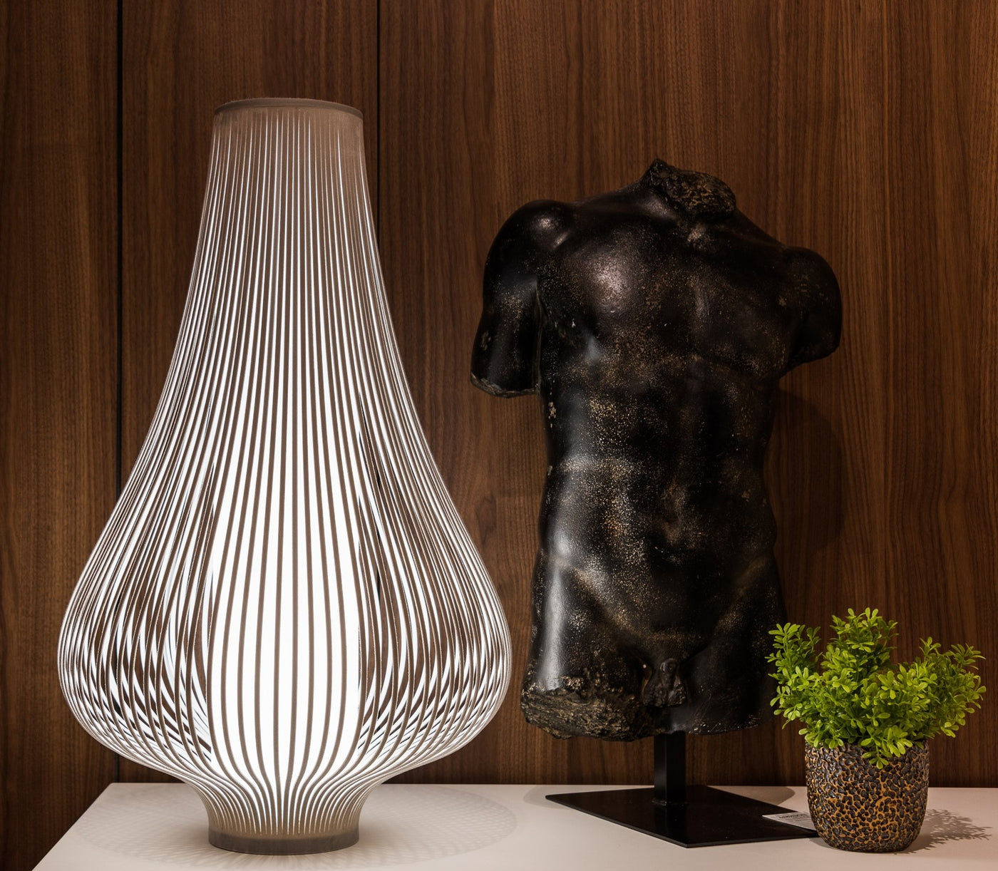 Uplight Group Blossom Table Lamp lit on a white console beside a bronze sculpture